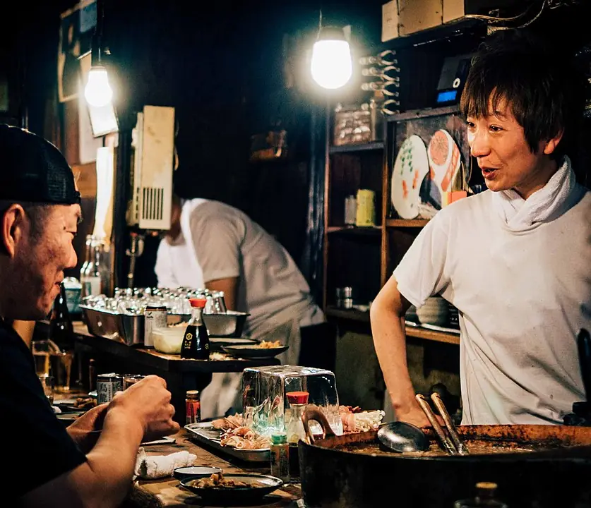 A cook chatting with a smiling guest at the counter