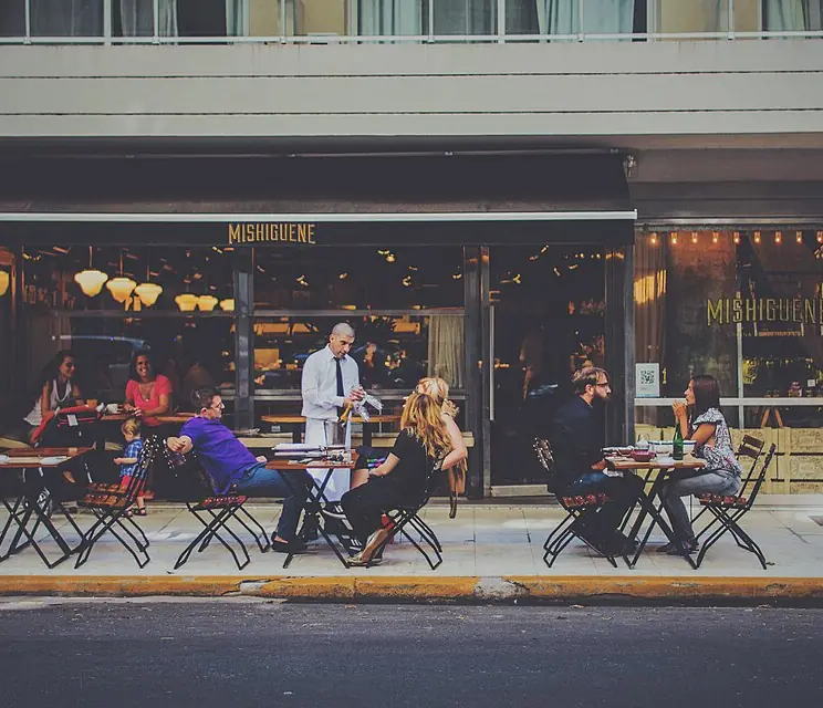 Guests at sidewalk tables while a server takes an order