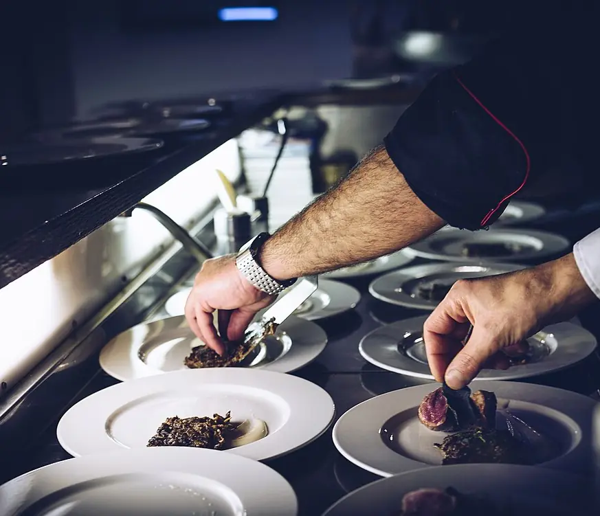 A chef placing the last touches on a row of plates